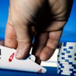 a hand holding cards next to stacks of poker chips