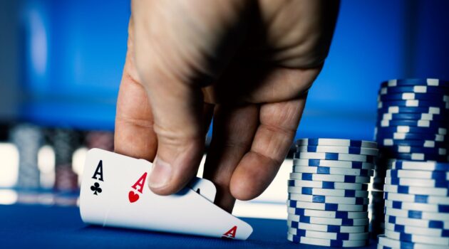 a hand holding cards next to stacks of poker chips